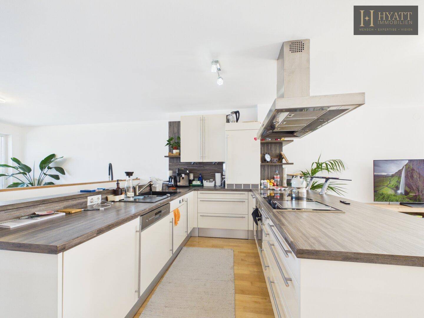 Moderne Einbauküche mit Kochinsel, Holz-Arbeitsplatten und Edelstahlgeräten.