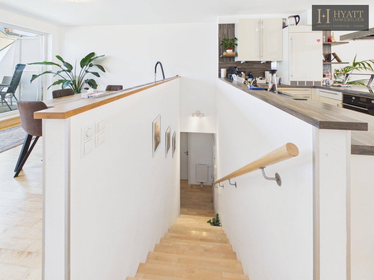 Treppenabgang vom offenen Wohnbereich in die untere Etage mit Holzgeländer.