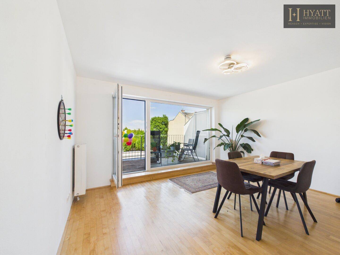 Essbereich mit Holztisch, modernen Stühlen und Zugang zu einem Balkon.