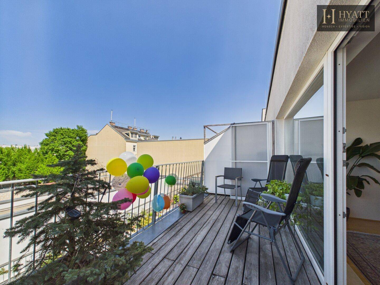 Geräumiger Balkon mit Holzdeck, Gartenmöbeln und Blick auf die Umgebung.
