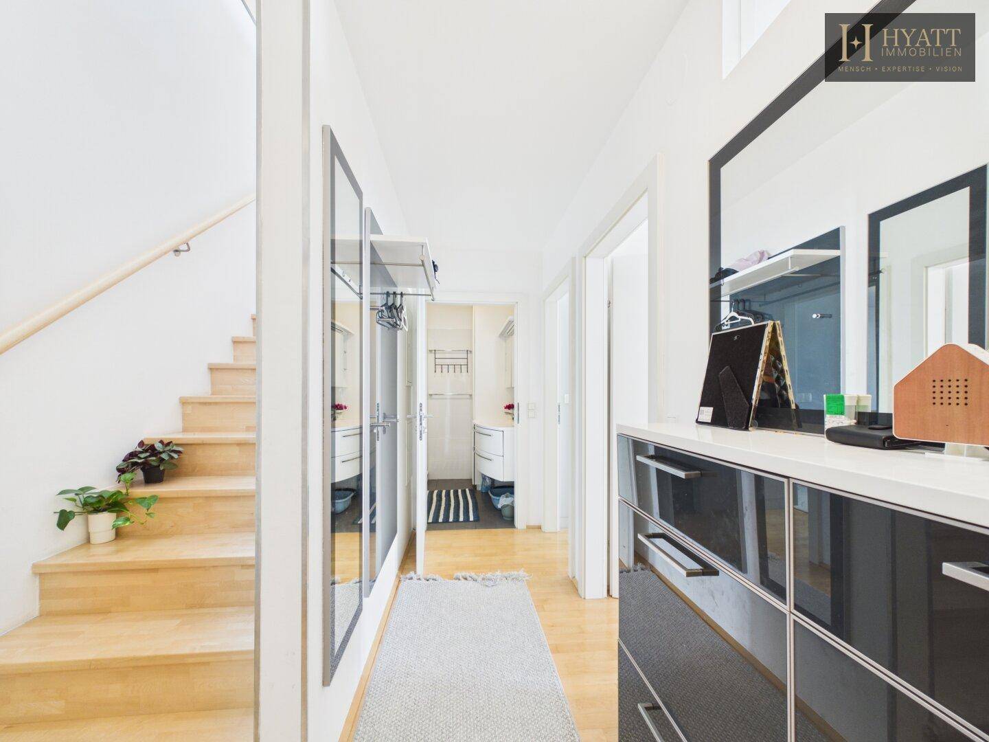 Flur mit Holzfußboden, Spiegeln und modernem Schuhschrank.