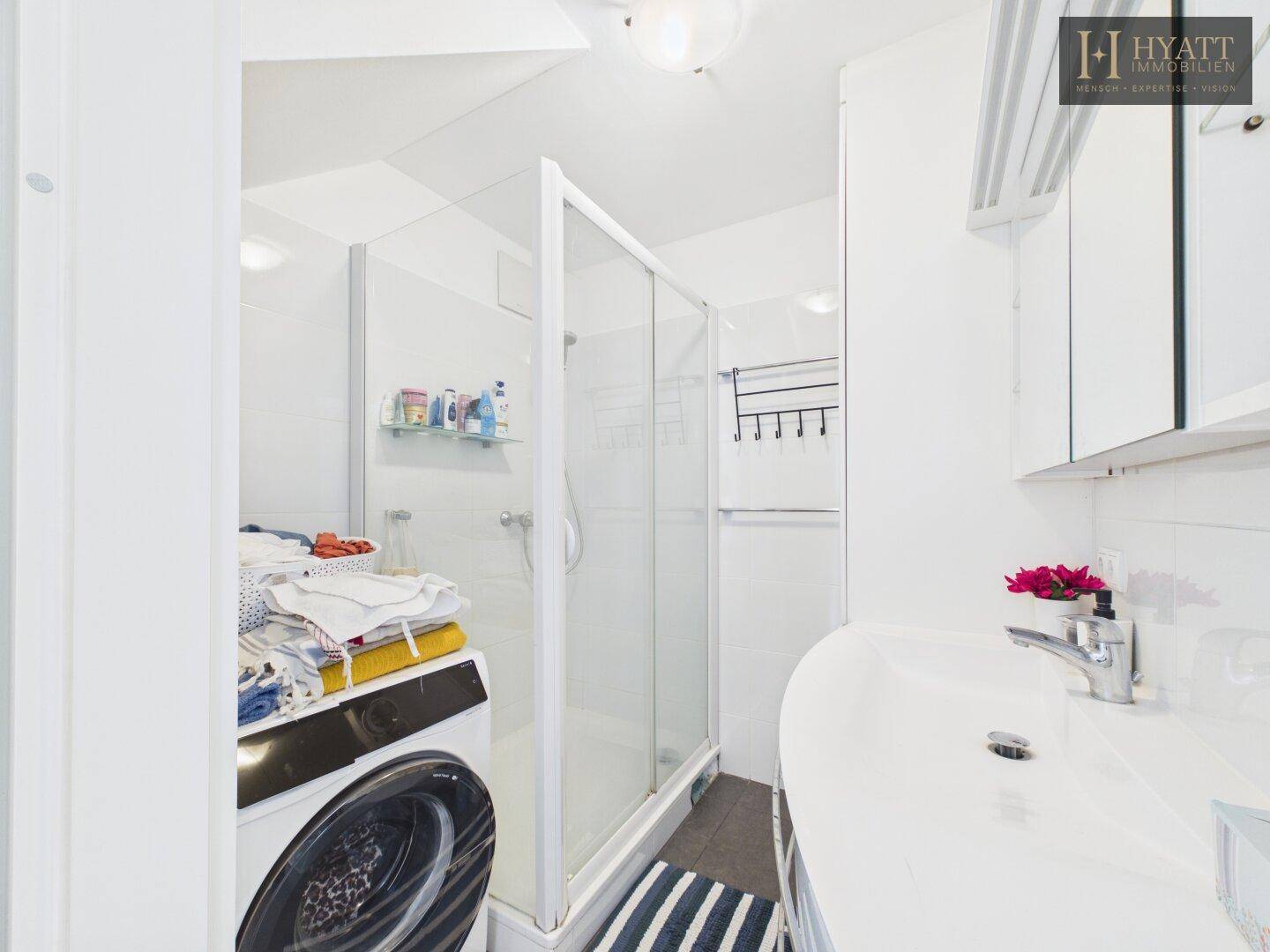 Modernes Badezimmer mit Dusche, Waschmaschine und Waschbecken.