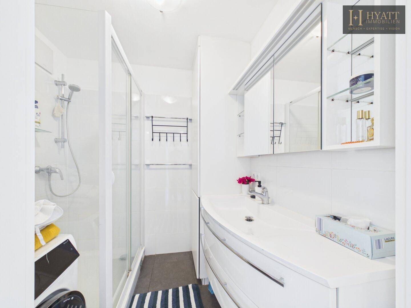 Helles Badezimmer mit Duschkabine, Waschbecken und Spiegelschrank.