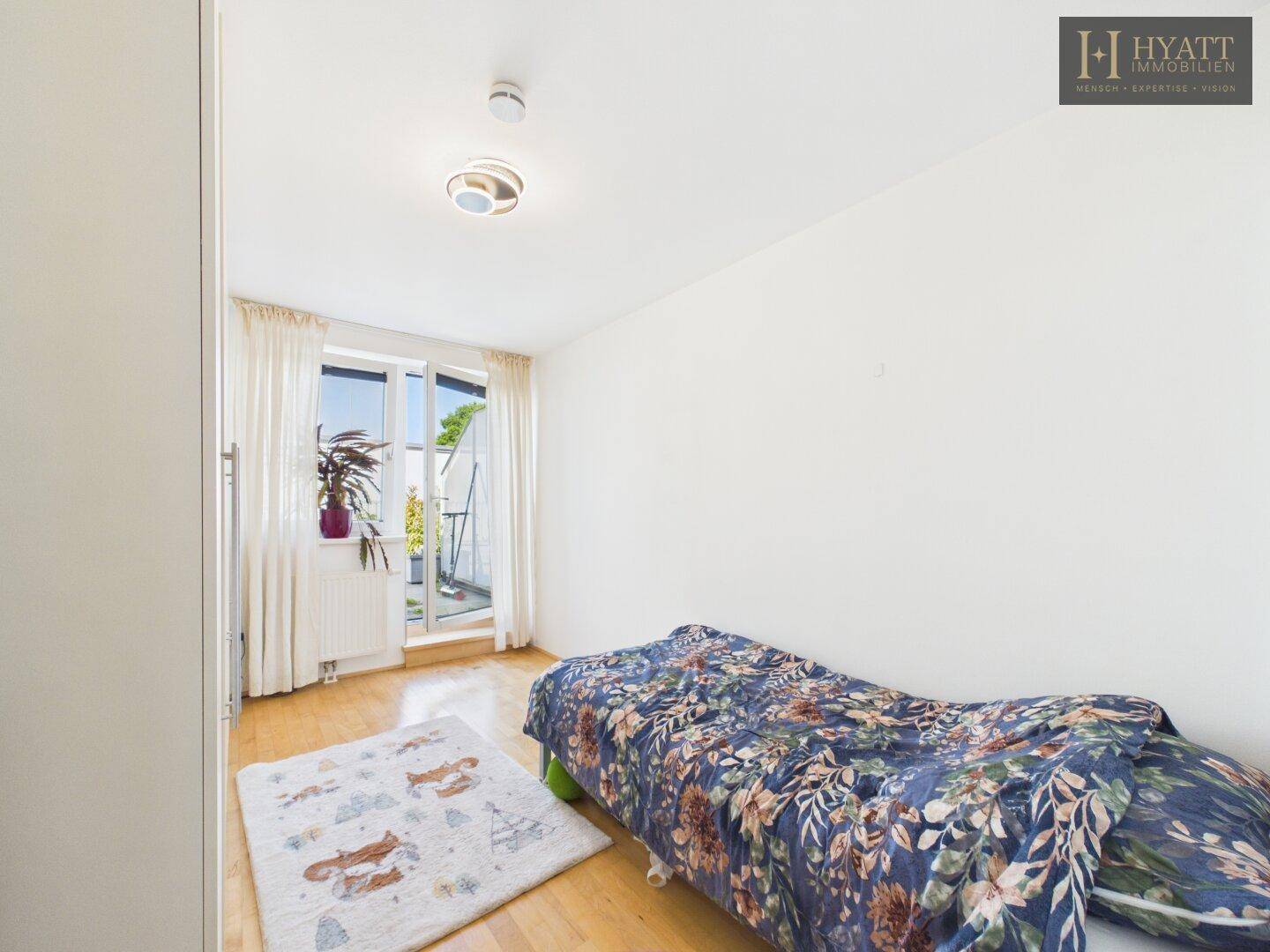 Kinderzimmer mit Einzelbett, Holzboden und Zugang zu einem Balkon.