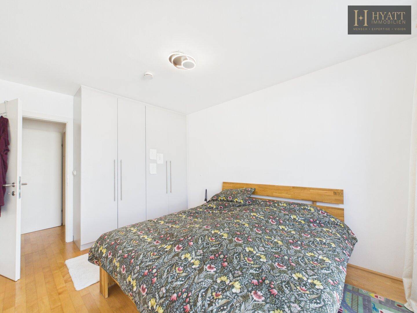 Schlafzimmer mit Doppelbett, Einbauschränken und Holzboden.
