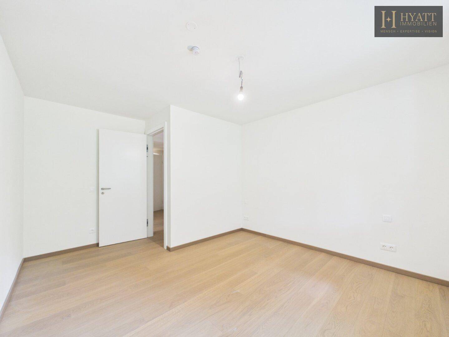 Leeres Zimmer mit hellem Holzparkett und weißen Wänden, bereit zur individuellen Gestaltung.