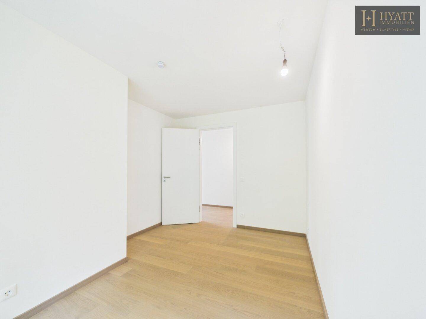 Leeres Zimmer mit hellem Holzparkett und weißen Wänden, vielseitig nutzbar.