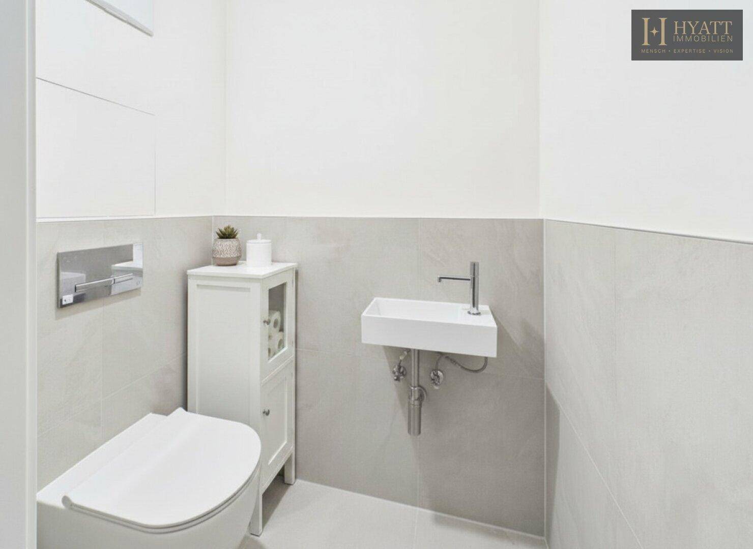 Modernes Gäste-WC mit wandhängendem Waschbecken und Toilette, in hellen Farbtönen.