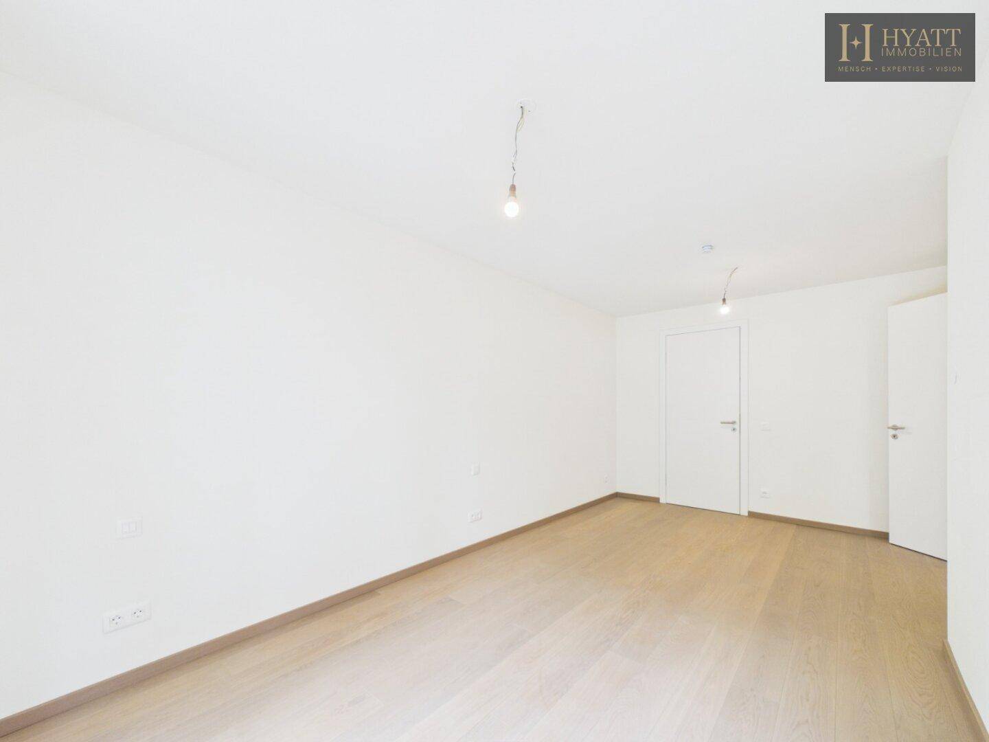 Leeres Schlafzimmer mit hellem Holzboden und weißen Wänden, bereit zur individuellen Gestaltung.