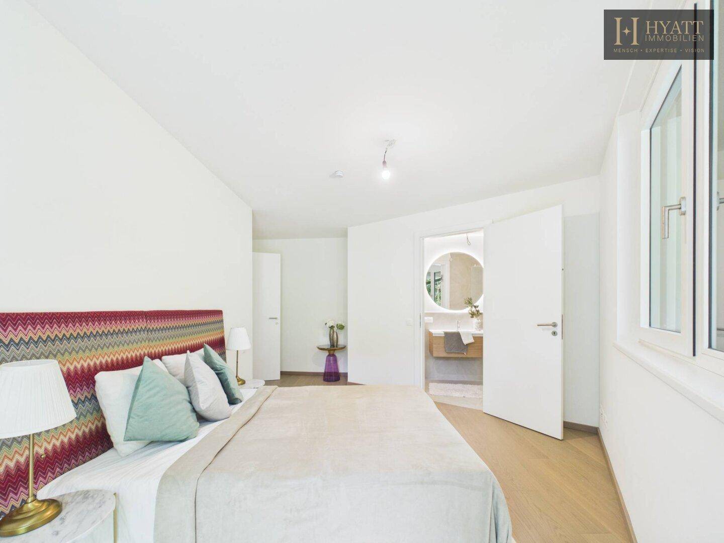 Helles Schlafzimmer mit Holzboden und direktem Zugang zu einem modernen Badezimmer.