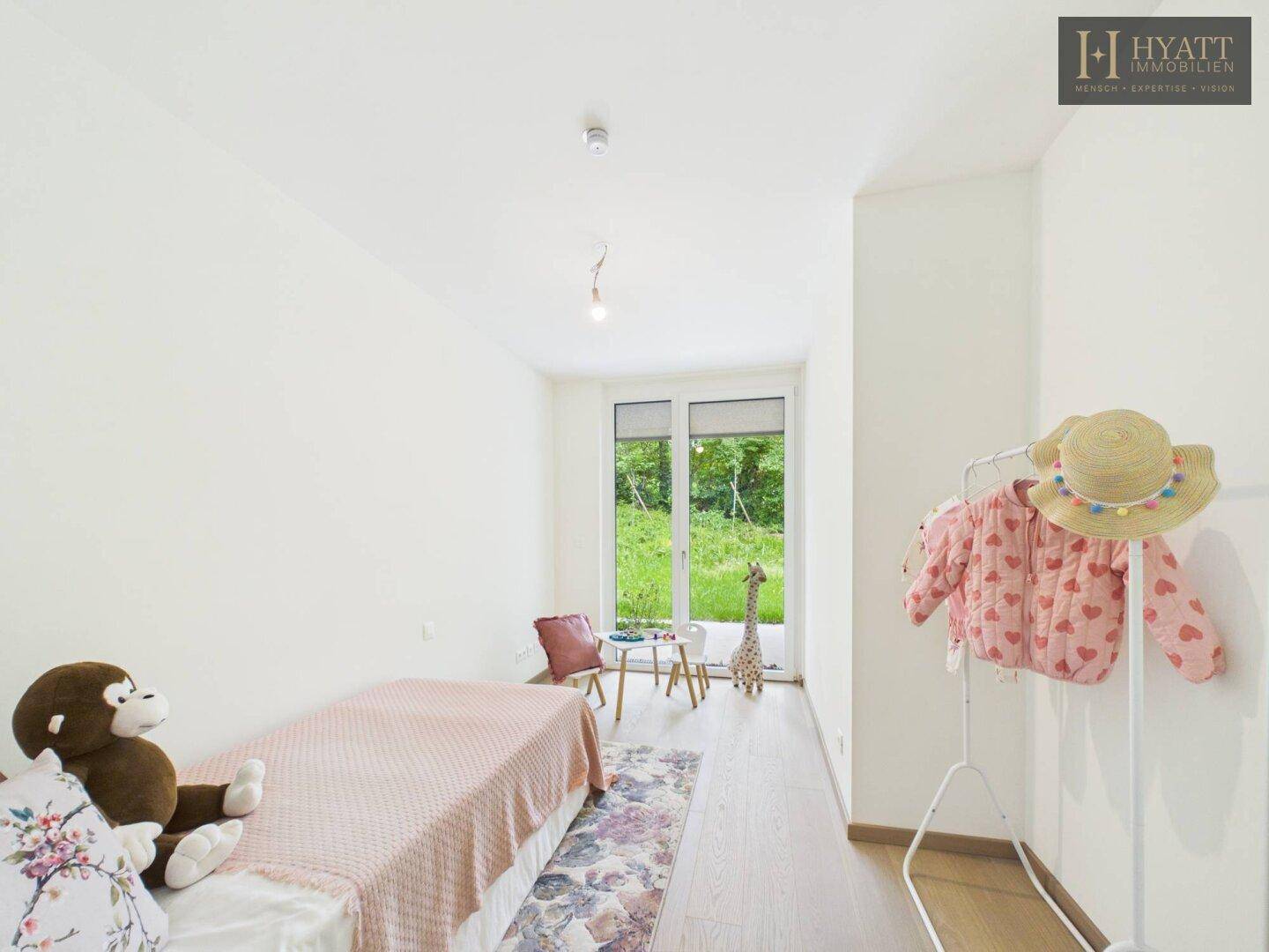 Kinderzimmer mit Holzboden, Spielzeug und Zugang zu einem kleinen Außenbereich.