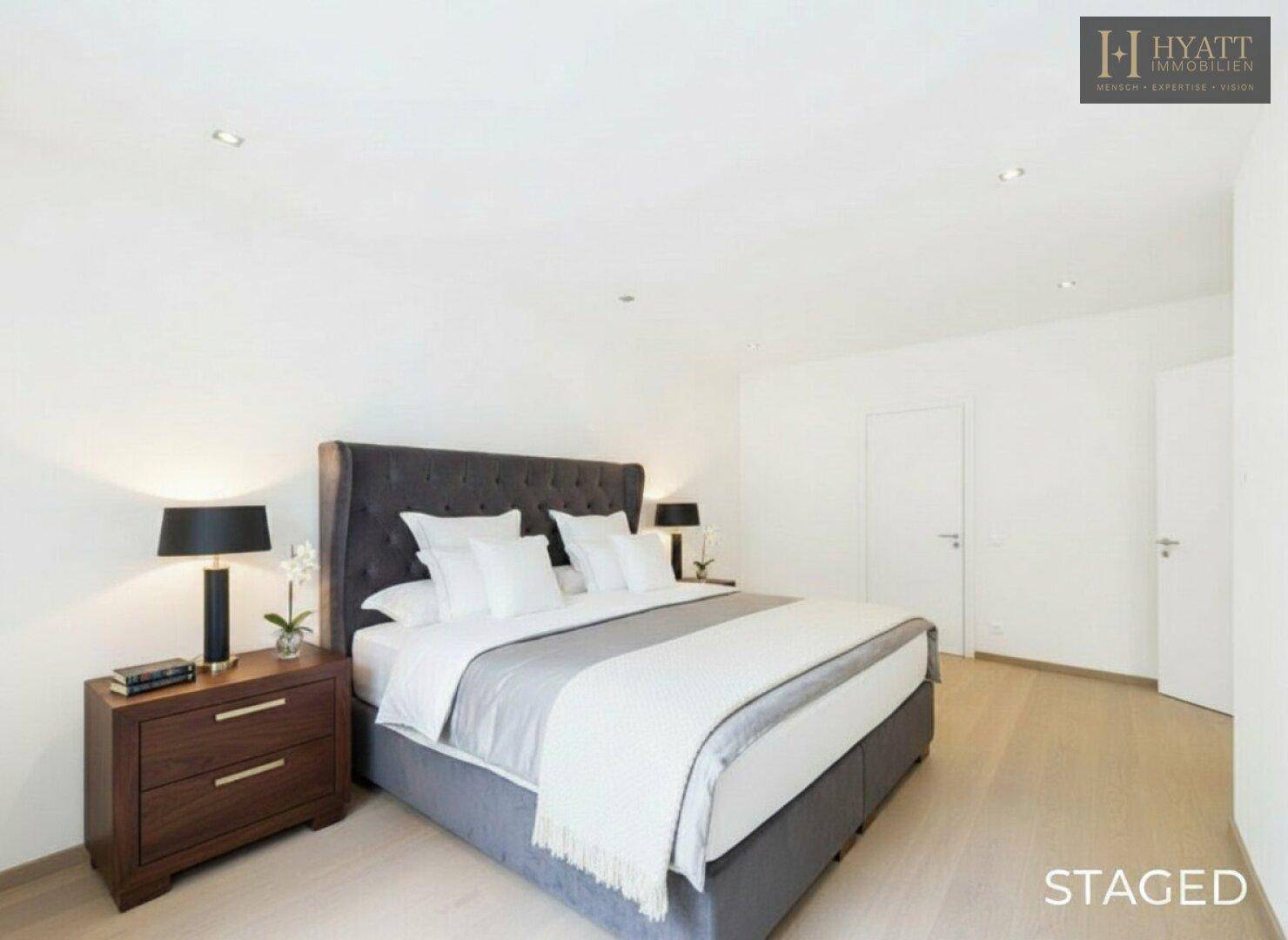 Modern inszeniertes Schlafzimmer mit großem Bett, Holzboden und indirekter Beleuchtung.