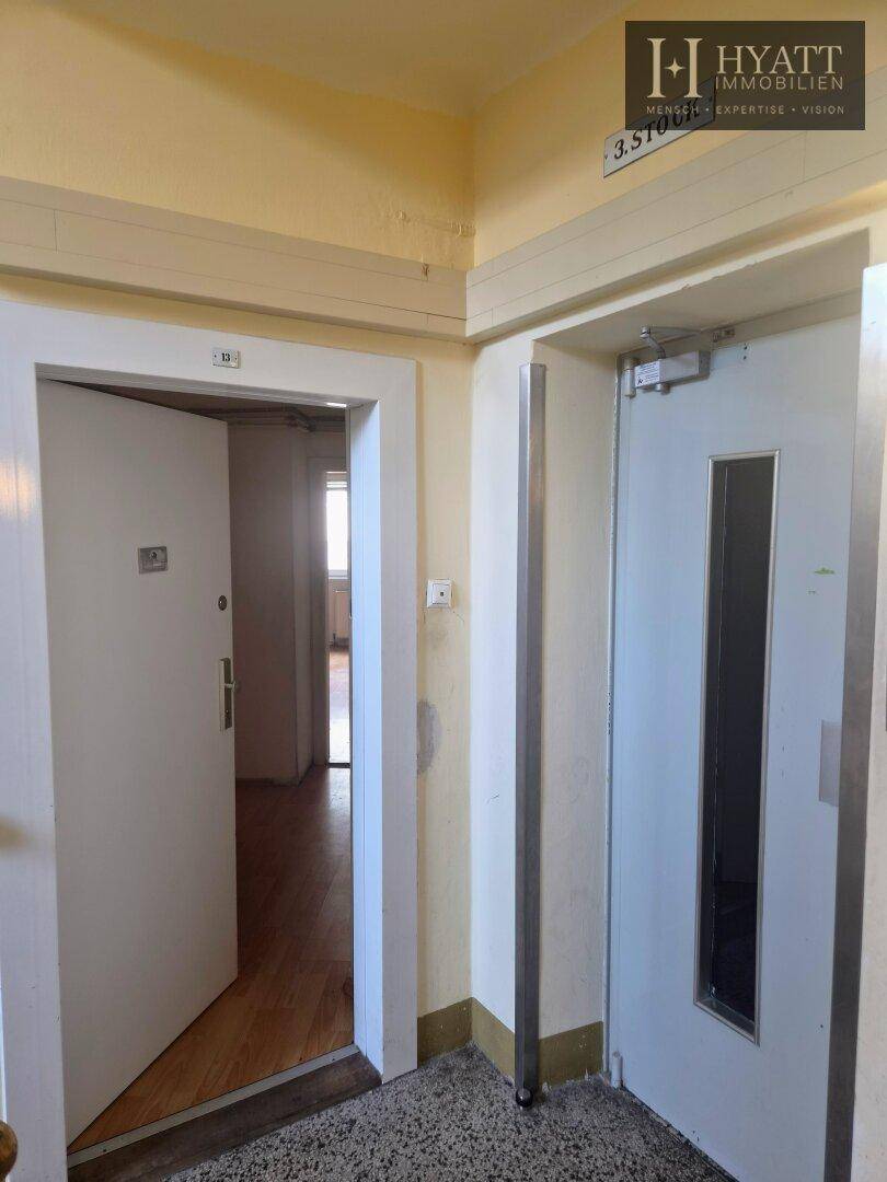 Eingangsbereich mit Aufzug und Zugang zu einer Wohnung, mit Terrazzoboden.