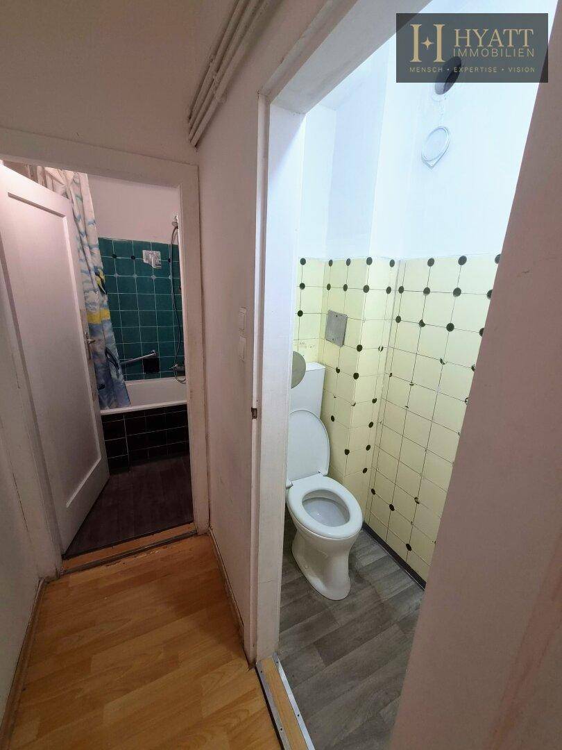 Separates WC mit gelben Fliesen und Toilette, neben dem Badezimmer gelegen.