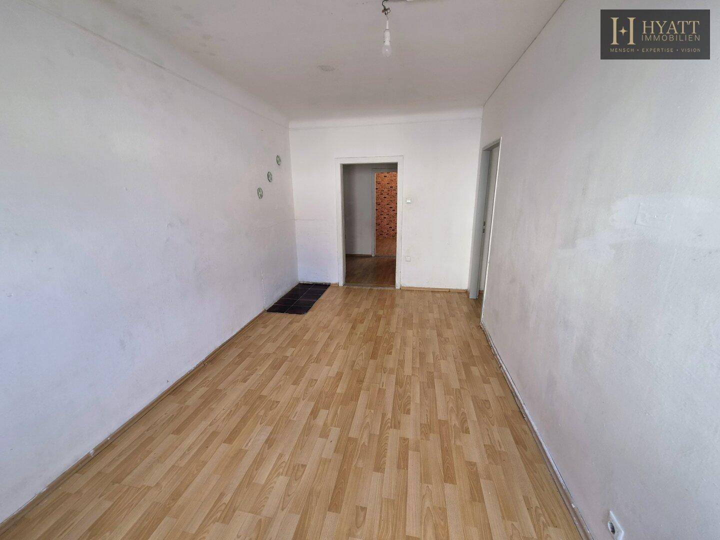 Leeres Wohnzimmer mit Holzboden und weiß gestrichenen Wänden, bereit zur Gestaltung.