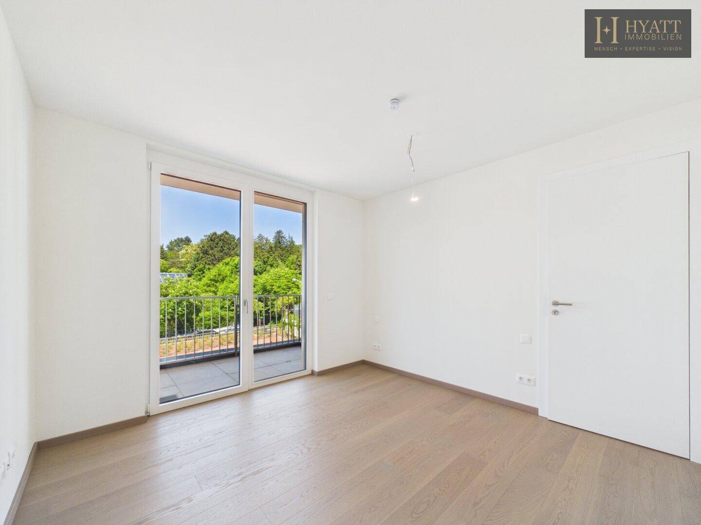 Helles Schlafzimmer mit großen Fenstern und Zugang zu einem privaten Balkon.