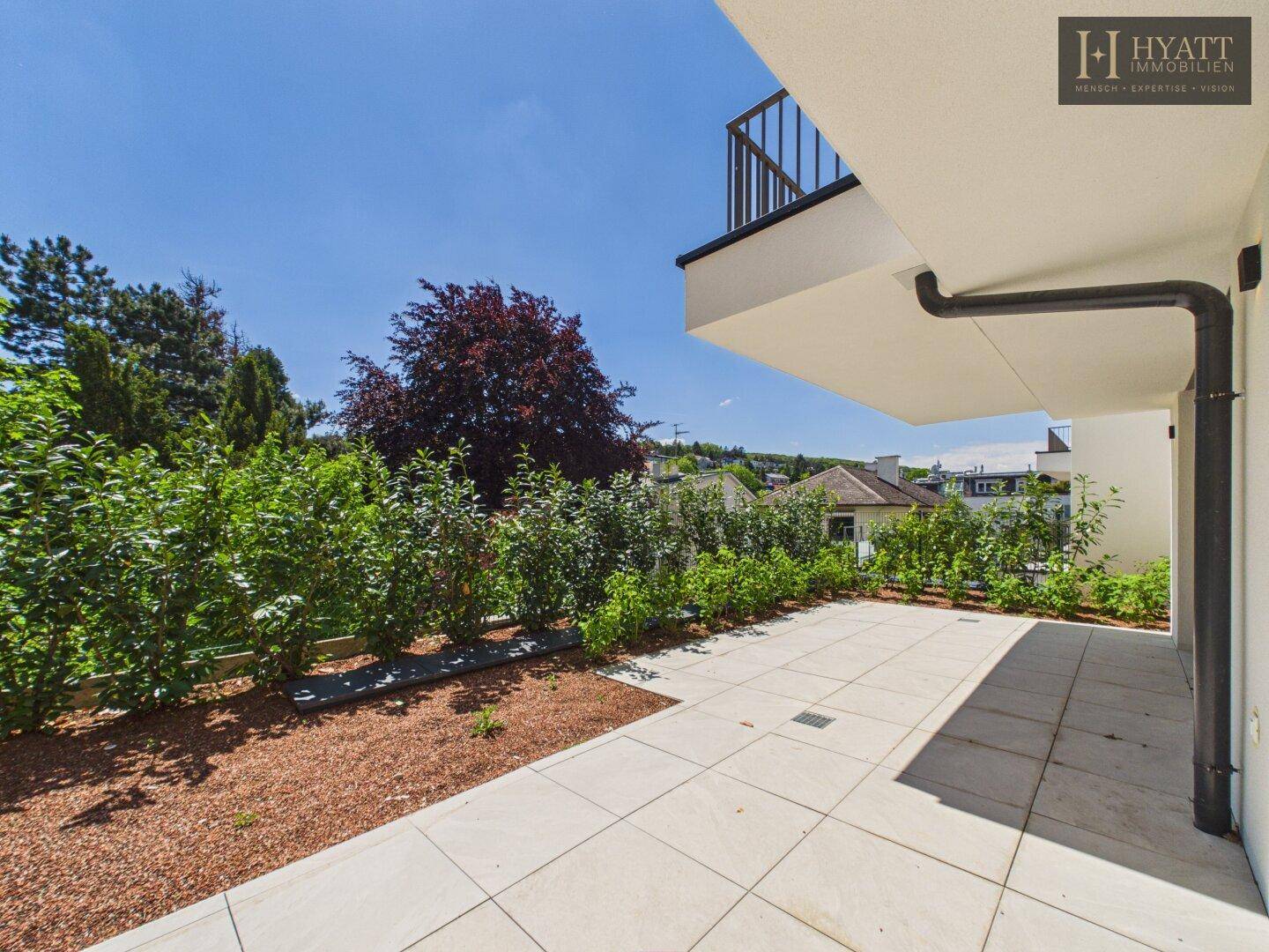 Weitläufige, unmöblierte Terrasse mit Fliesenboden und Blick auf die Umgebung.