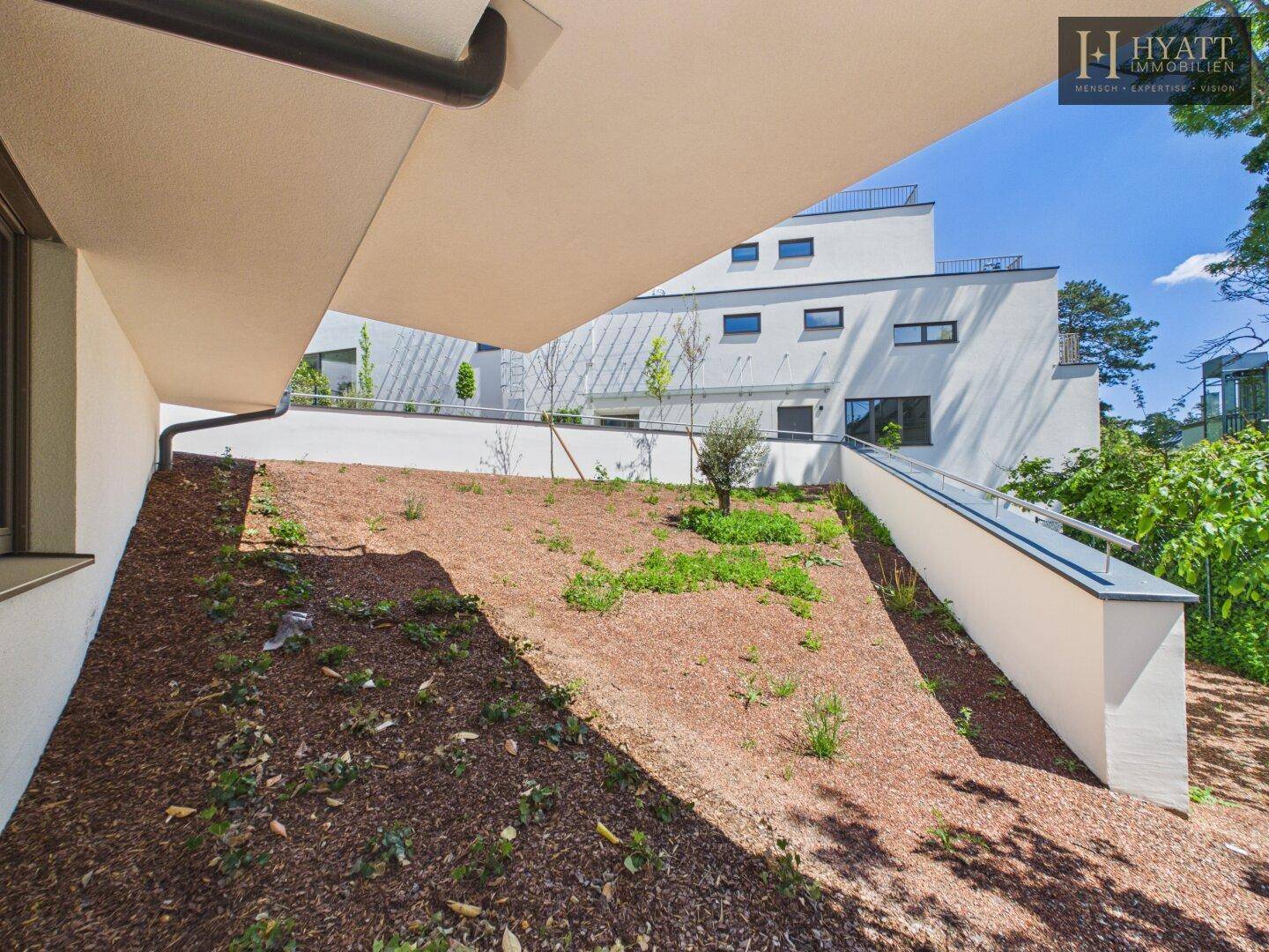 Naturbelassener Gartenbereich mit leichter Hanglage und junger Bepflanzung.