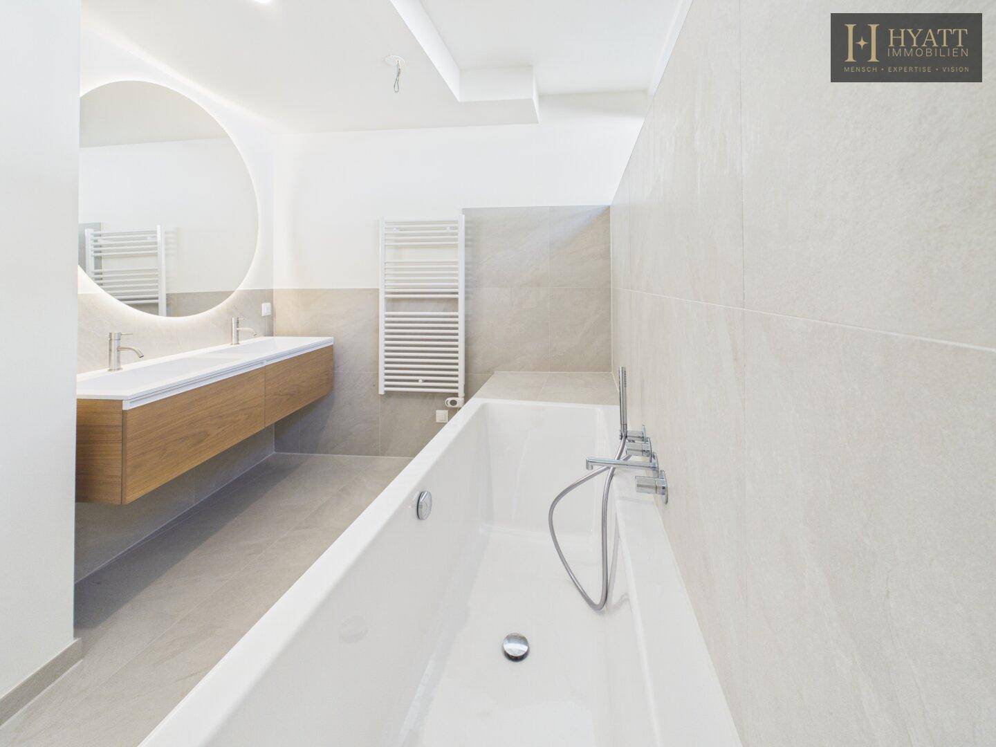 Elegantes Badezimmer mit Badewanne, modernem Waschtisch und indirekter Beleuchtung.
