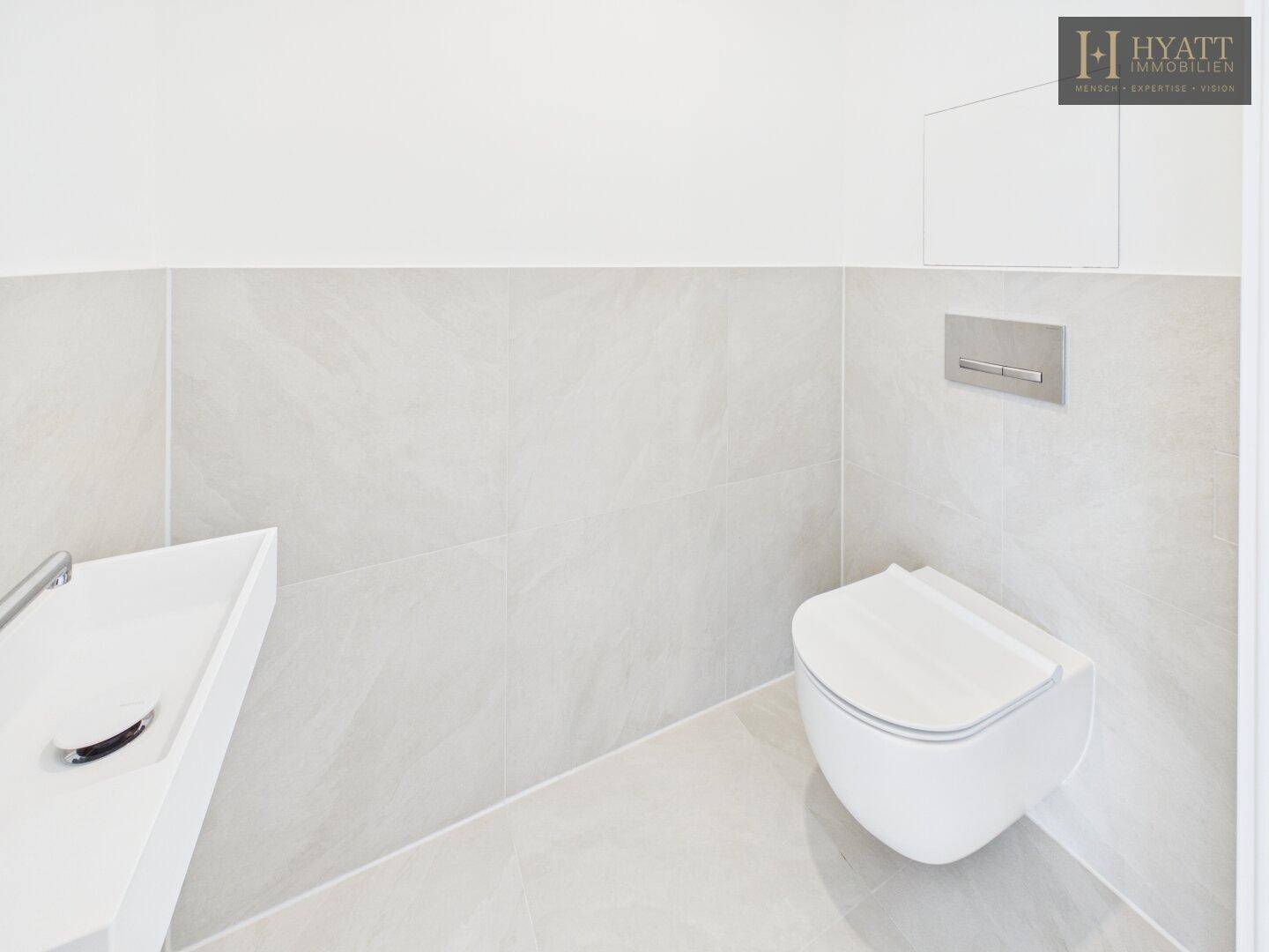 Modernes Gäste-WC mit wandhängender Toilette und kleinem Waschbecken.