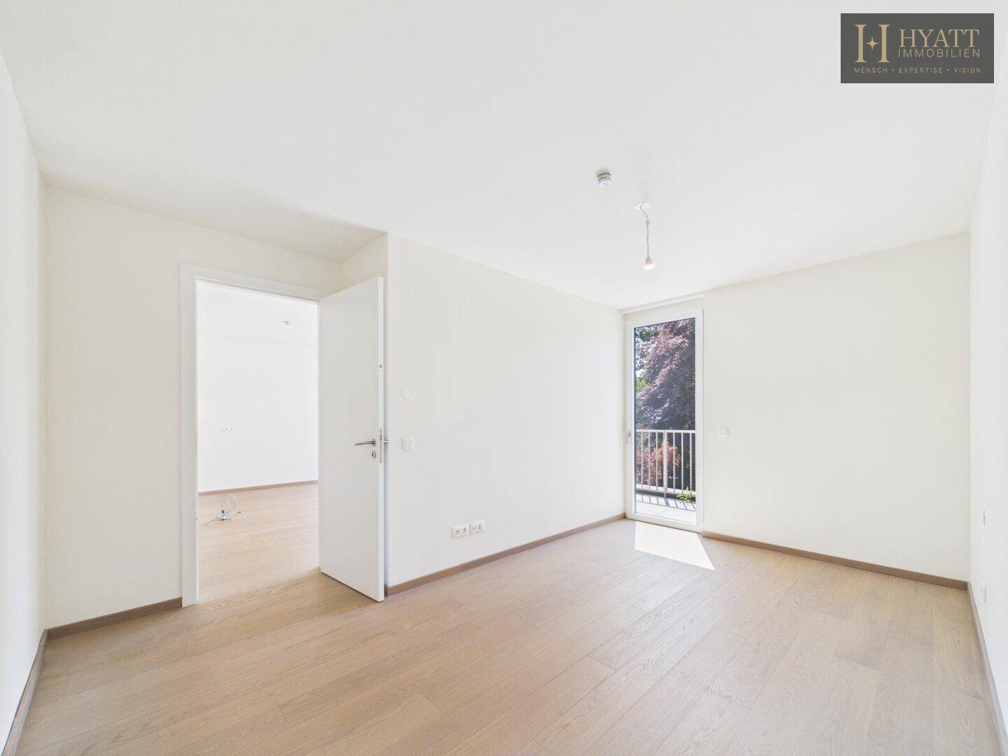 Helles, unmöbliertes Schlafzimmer mit Parkettboden und Zugang zum Balkon.