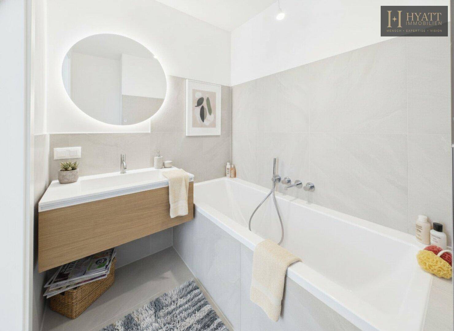 Modernes Badezimmer mit Badewanne, schwebendem Waschtisch und beleuchtetem Spiegel.
