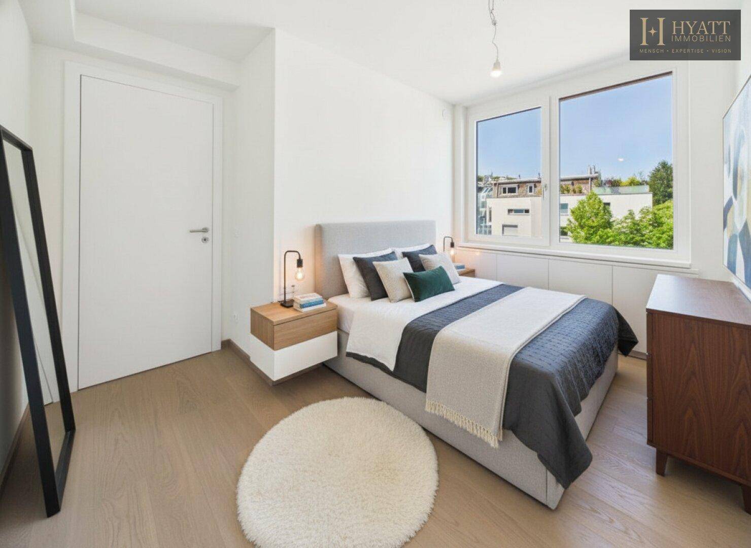Helles Schlafzimmer mit modernem Bett, Nachttischen und großem Fenster.