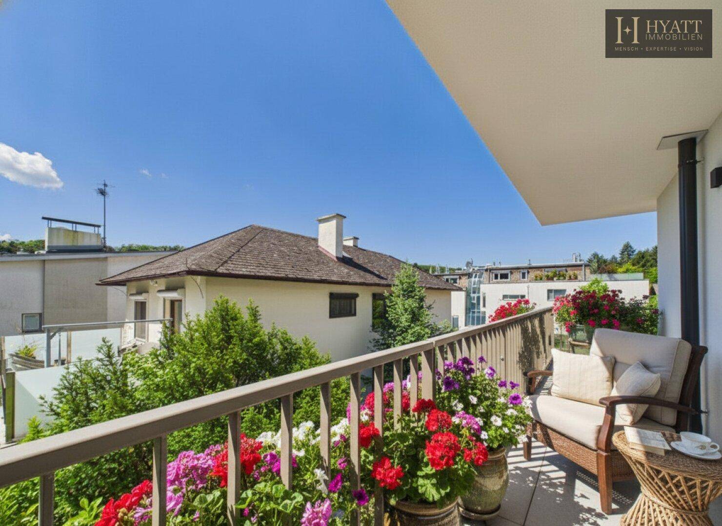 Sonniger Balkon mit Blumenkästen und bequemen Gartenmöbeln, ideal zum Entspannen.