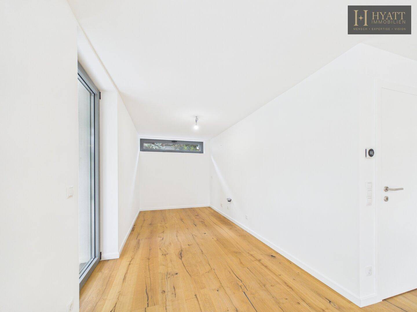Helles Zimmer im Dachgeschoss mit schrägen Wänden und Holzboden, ideal als Schlaf- oder Arbeitszimmer.