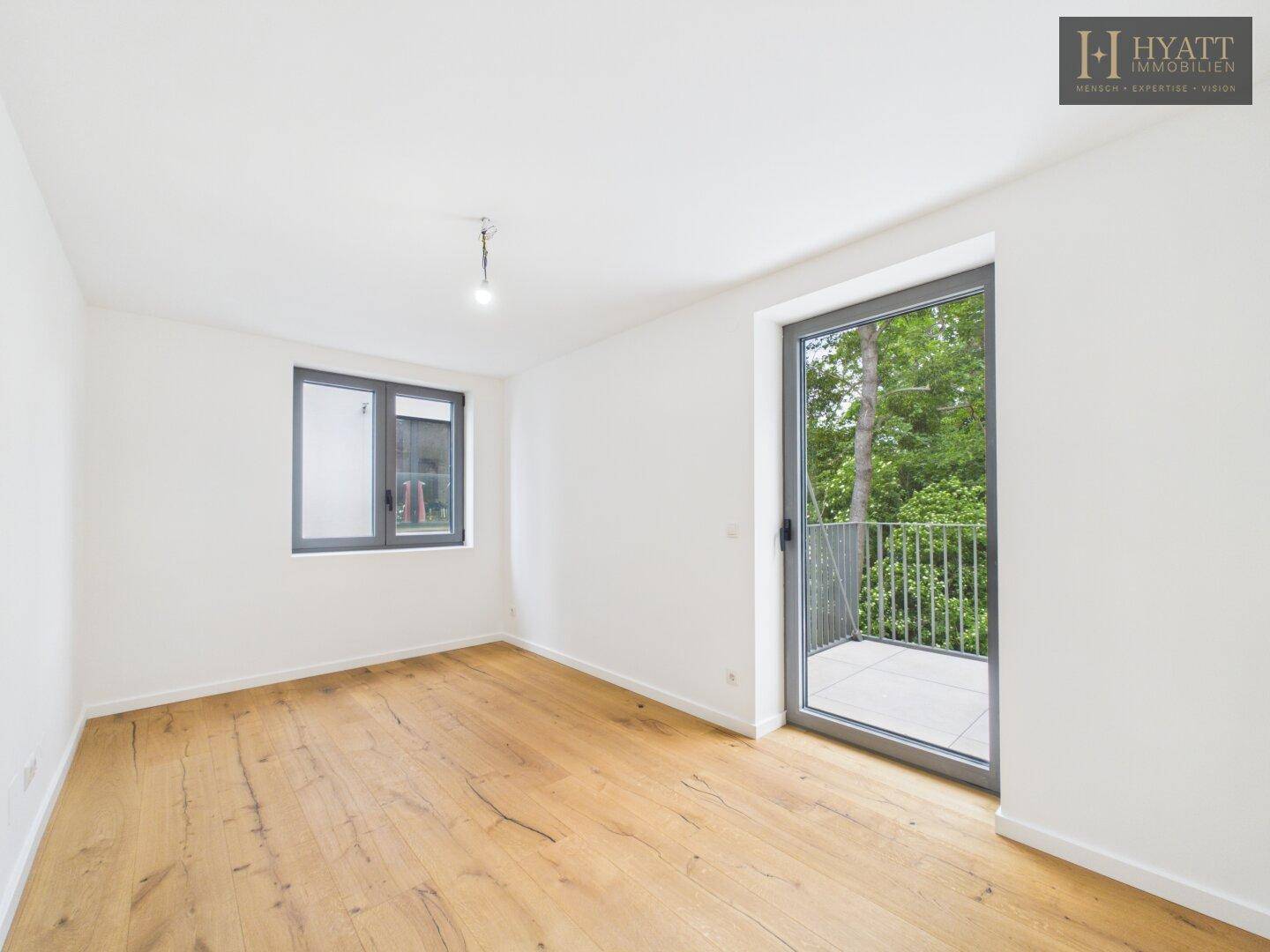 Schlafzimmer mit Zugang zu einem Balkon und großen Fenstern, die viel Tageslicht hereinlassen.