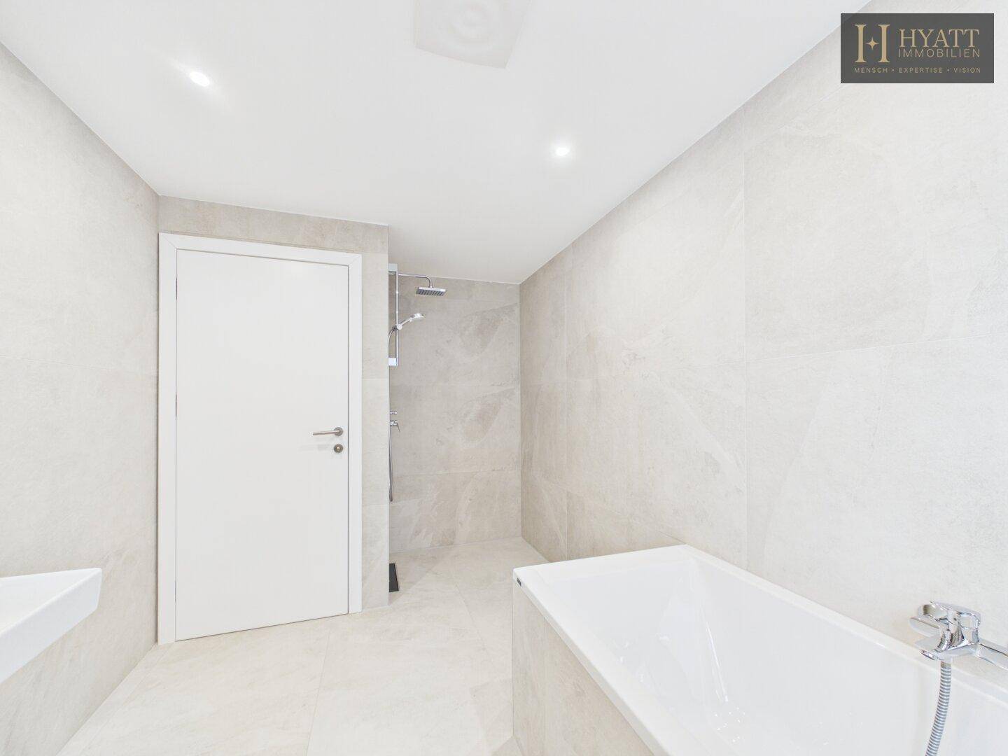 Elegantes Badezimmer mit Badewanne und Duschbereich, ausgestattet mit modernen Fliesen.