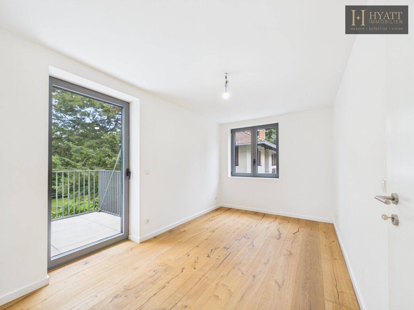Helles Schlafzimmer mit Holzboden und direktem Zugang zum Balkon, bietet eine angenehme Atmosphäre.
