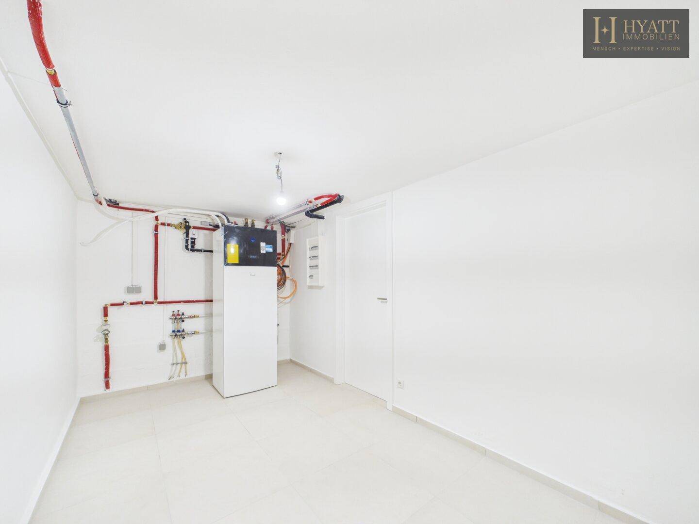 Technikraum im Keller mit moderner Heizungsanlage und sichtbaren Installationen.