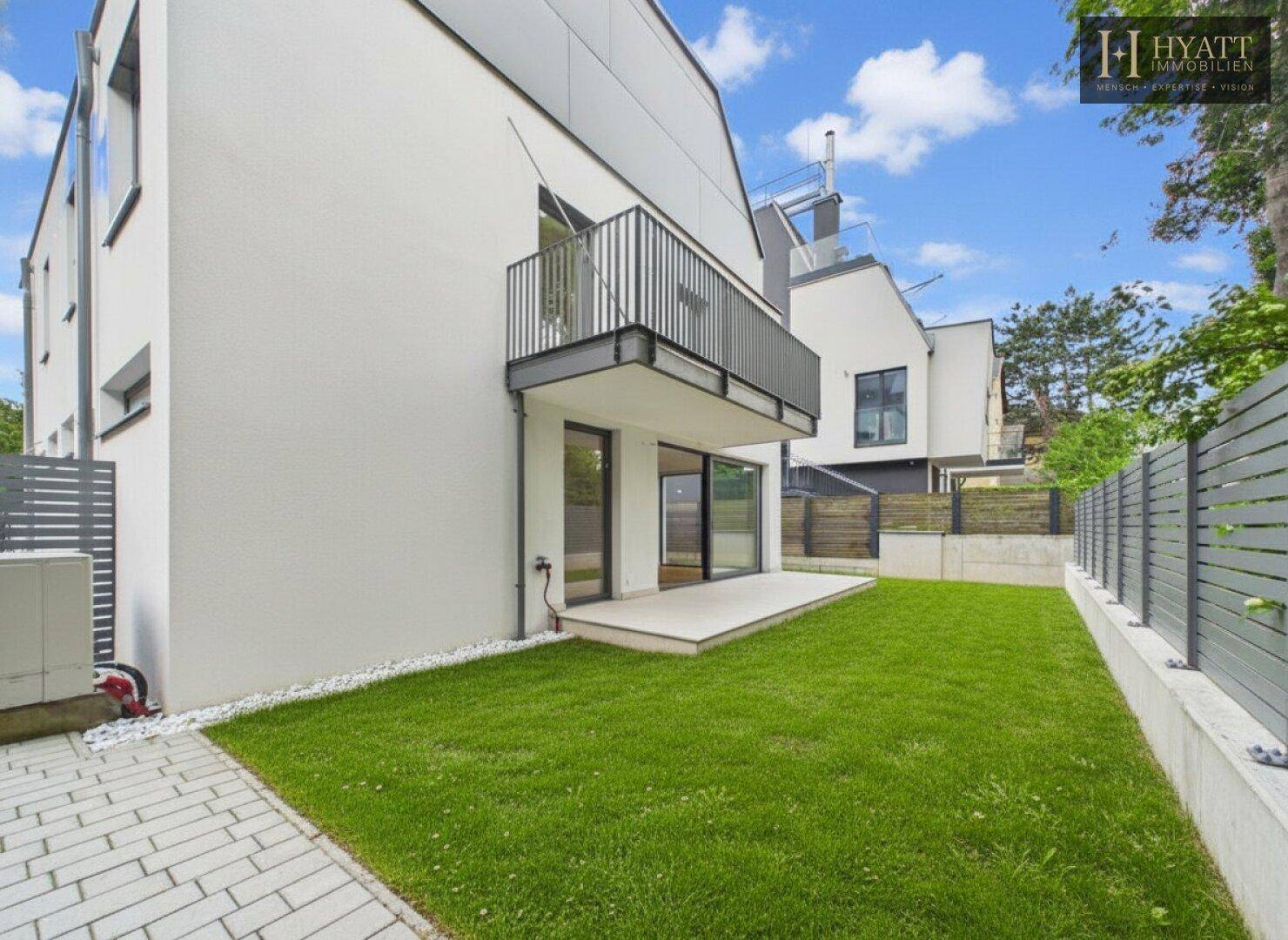 Ansicht der modernen Immobilie von der Seite mit Gartenbereich und Zugang zur Terrasse.