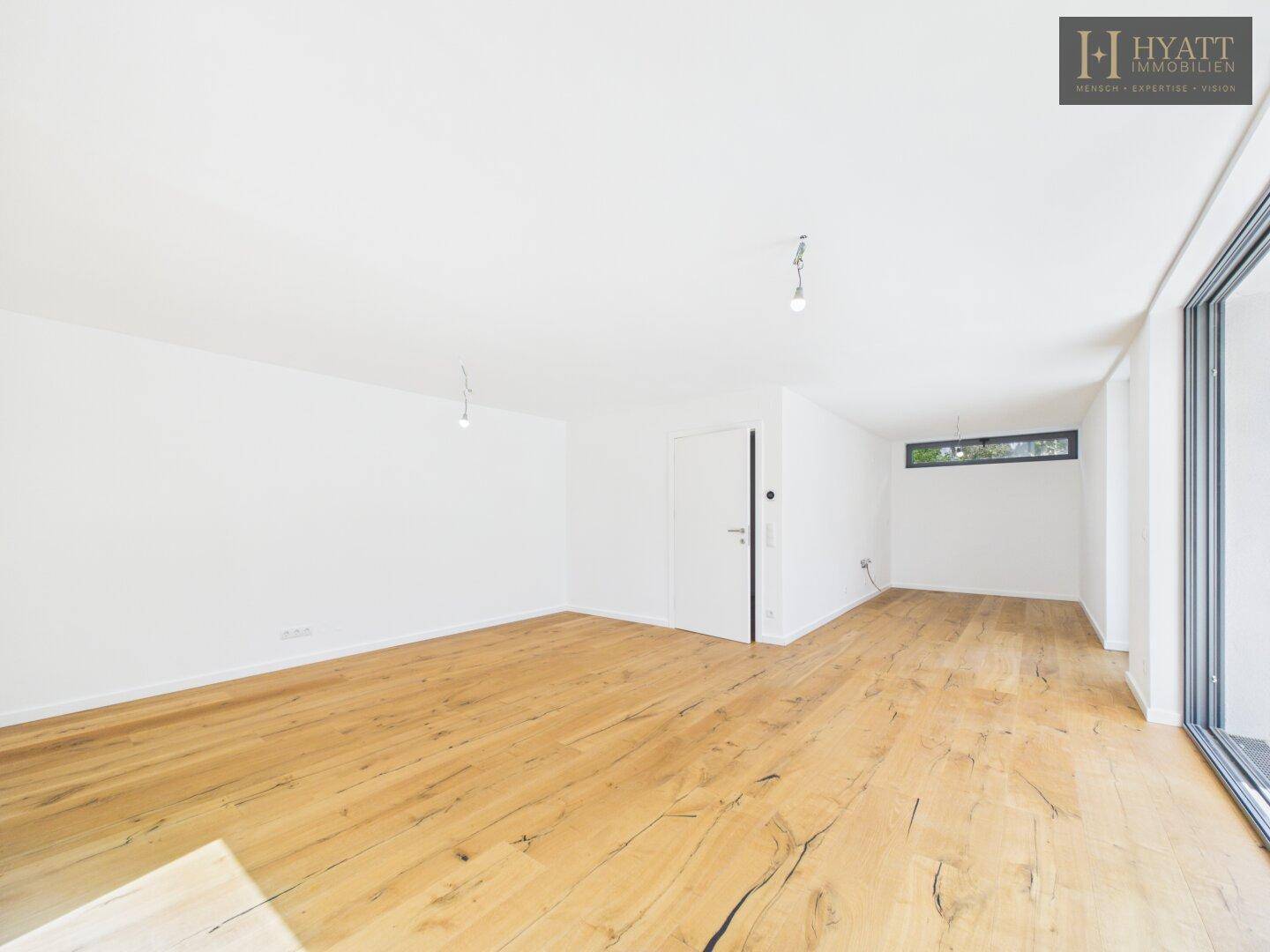 Geräumiges Wohnzimmer mit viel Tageslicht, Eichenparkett und moderner Ästhetik.