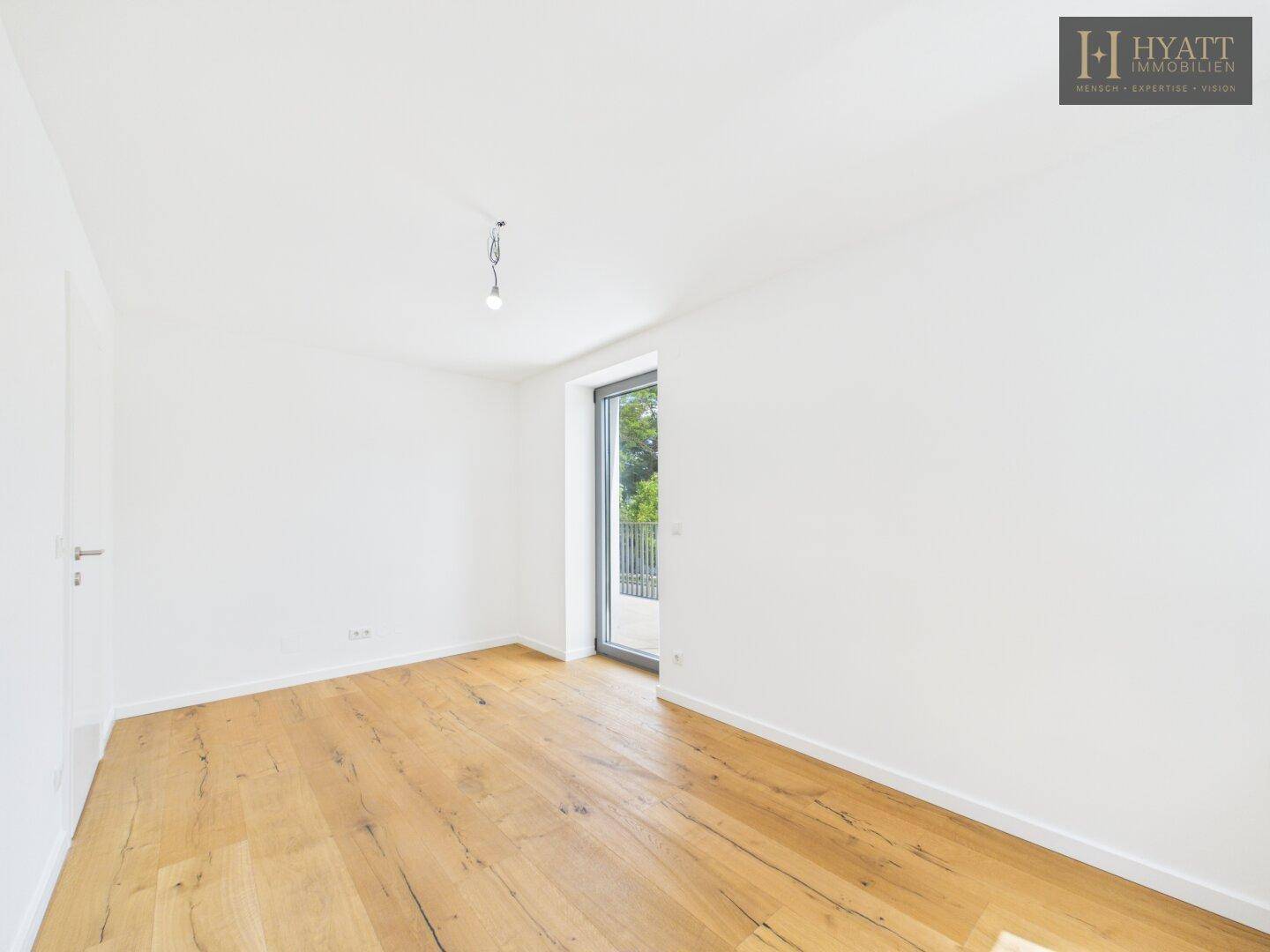 Helles Schlafzimmer mit Holzboden und direktem Zugang zu einem Balkon.
