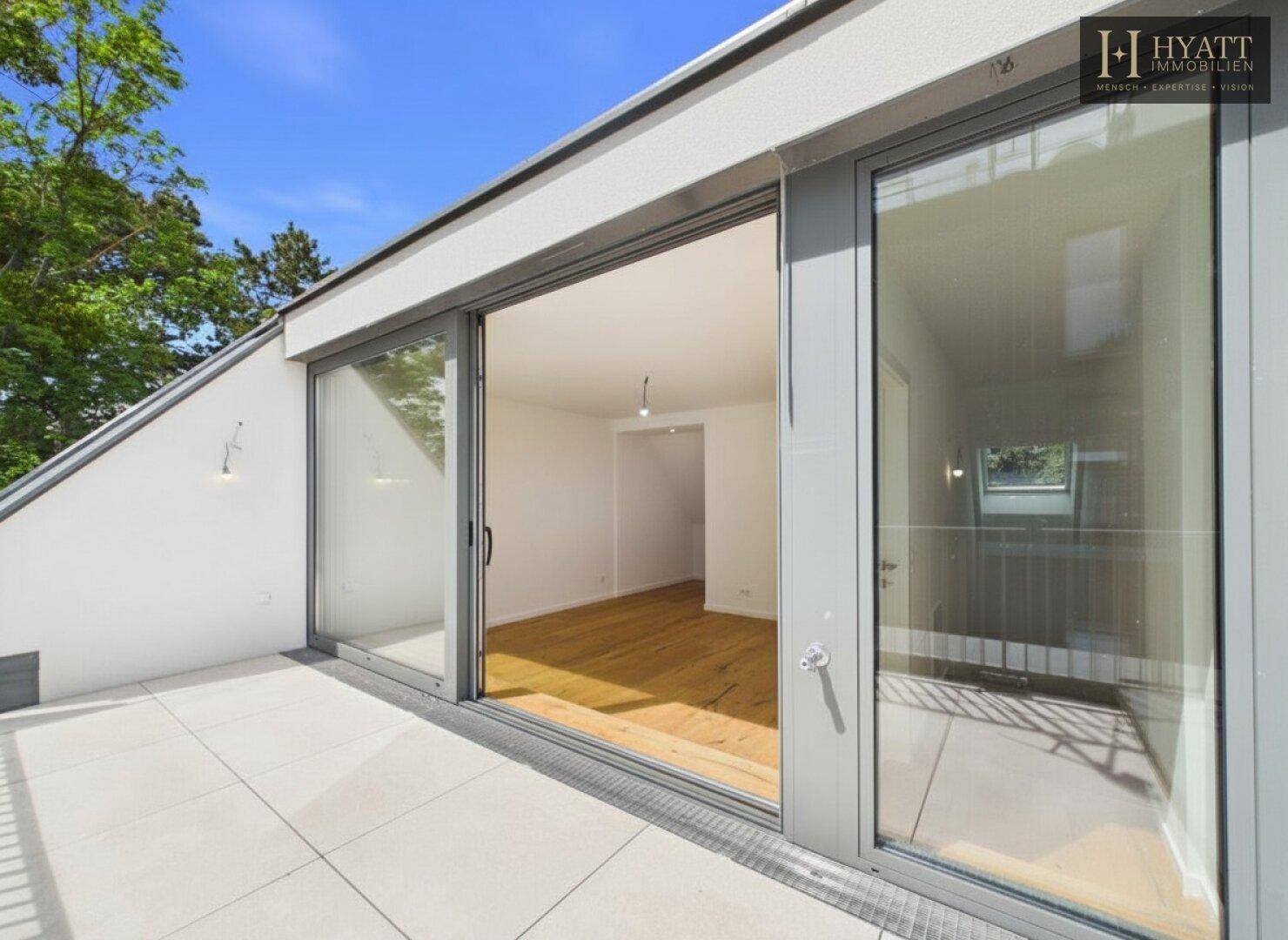 Große Dachterrasse mit Fliesenboden und weitem Blick, zugänglich durch Glasschiebetüren.