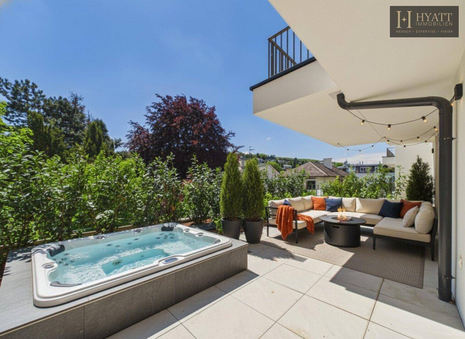 Großzügige Terrasse mit Whirlpool und gemütlicher Lounge-Ecke, umgeben von viel Grün.