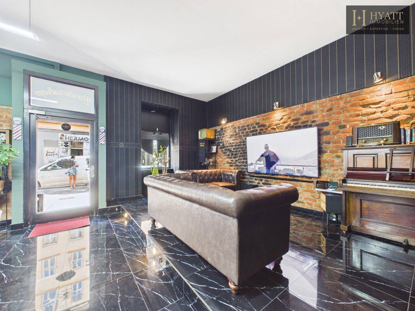 Gemütlicher Loungebereich mit Ledersofa, Fernseher und Vintage-Möbeln für entspannte Momente.