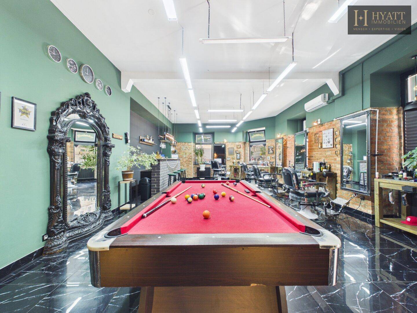 Billardtisch mit rotem Filz und opulentem Spiegel in einem stilvollen Friseursalon.