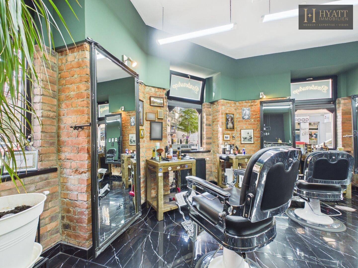 Detailansicht eines Friseurplatzes mit klassischem Stuhl, großem Spiegel und Ziegelwand.