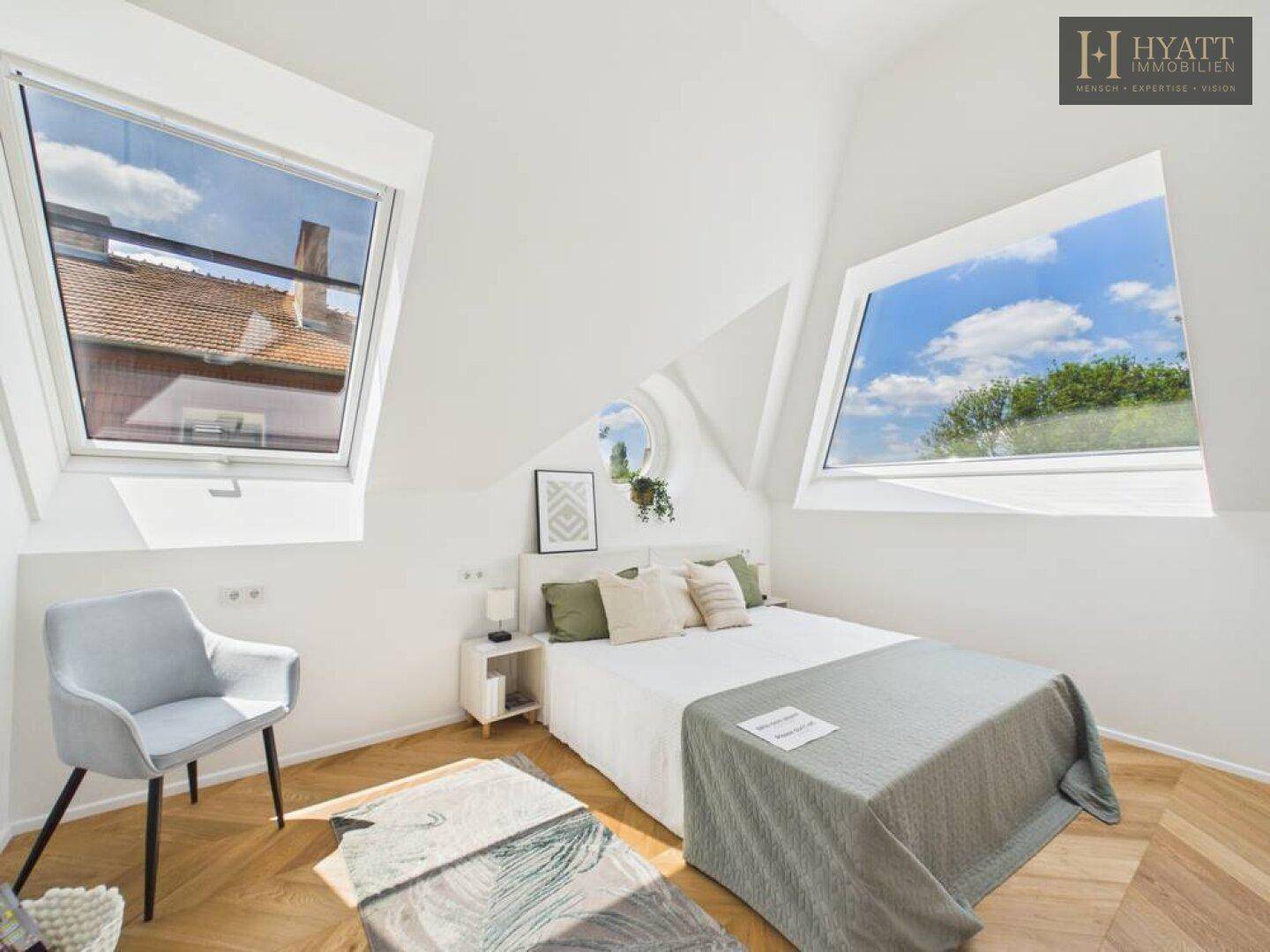 Helles Schlafzimmer im Dachgeschoss mit schrägen Decken, zwei großen Dachfenstern und Parkettboden.