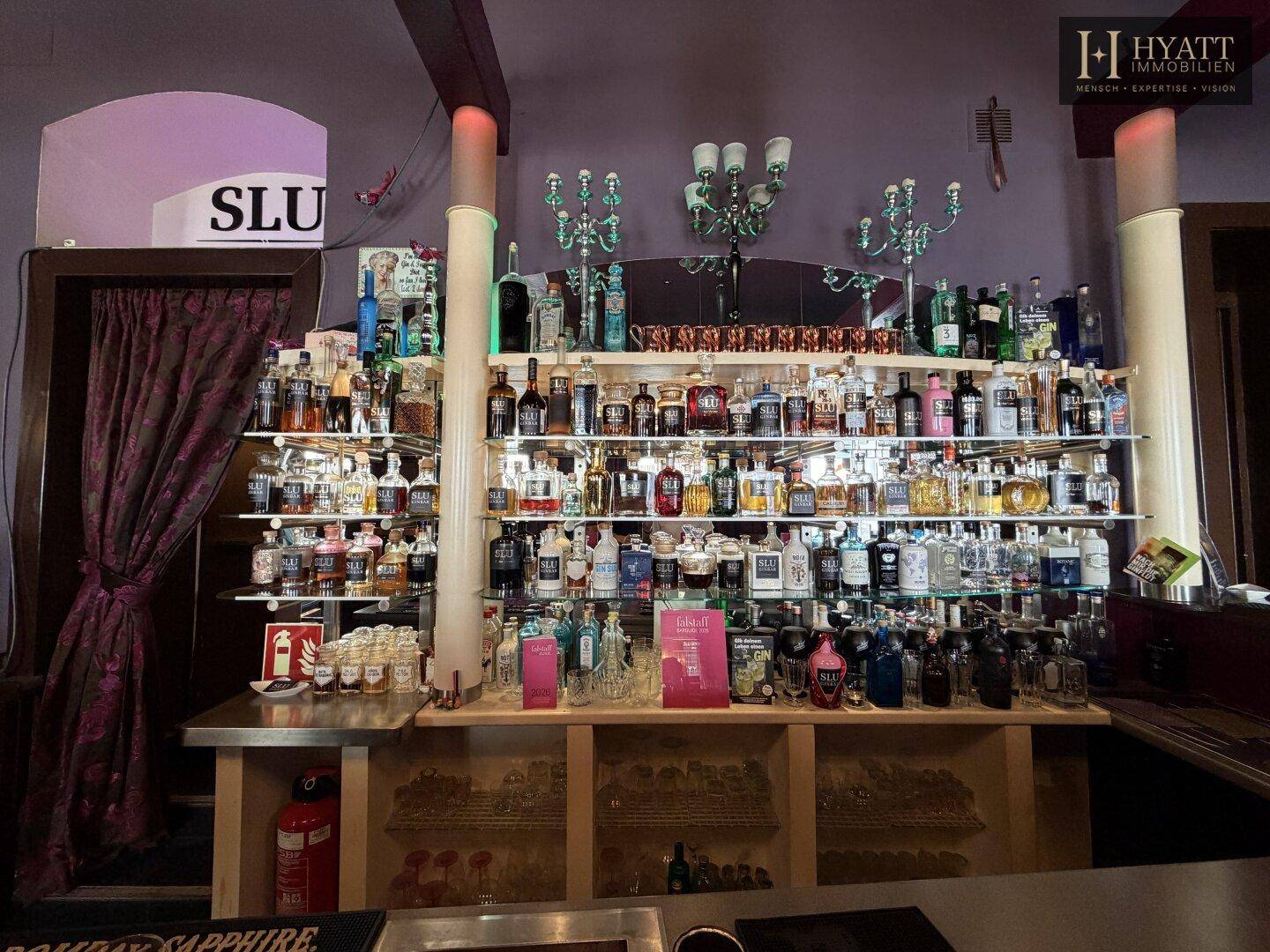 Gut sortiertes Spirituosenregal hinter der Bar mit einer Vielzahl von Flaschen und Dekorationen.