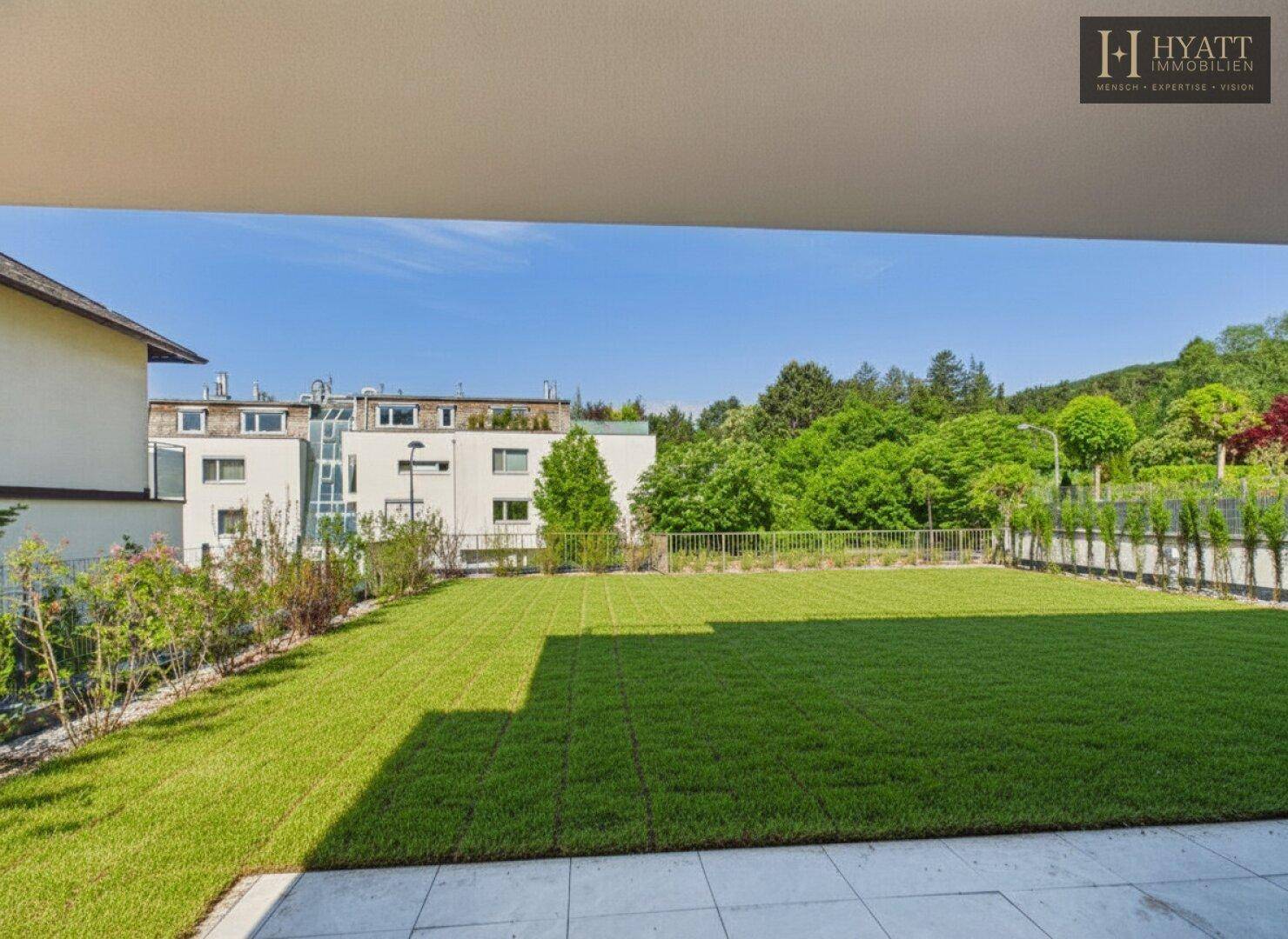 Weitläufige Rasenfläche mit Blick auf die umliegende grüne Landschaft und moderne Gebäude.