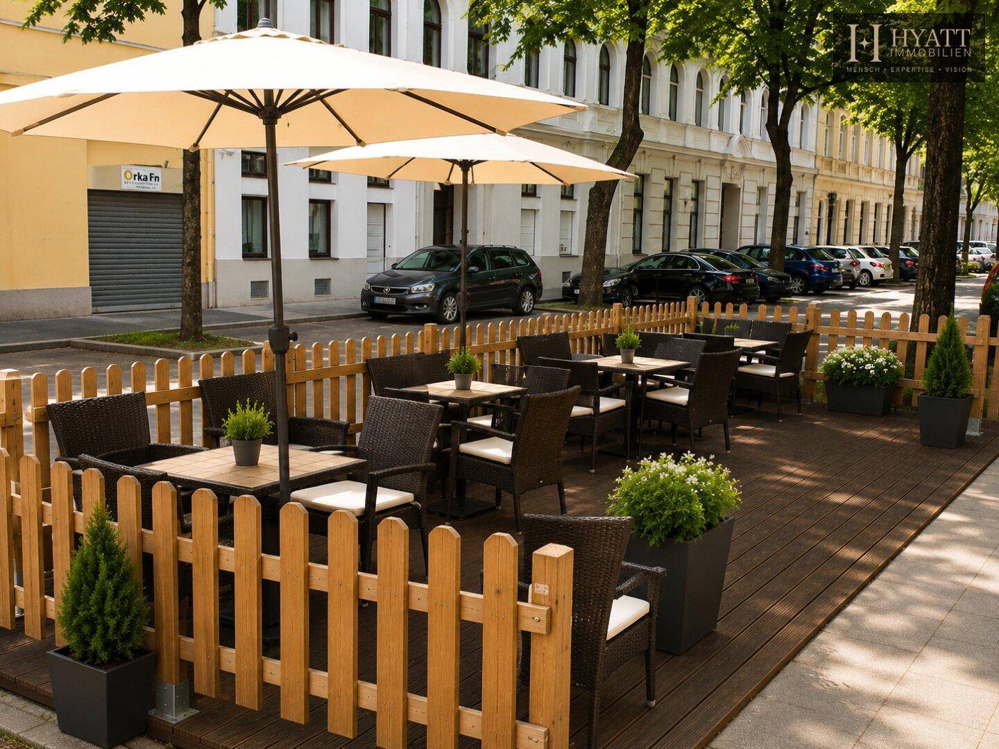 Einladende Außenterrasse mit Holzzaun, Sonnenschirmen und bequemen Sitzgelegenheiten.