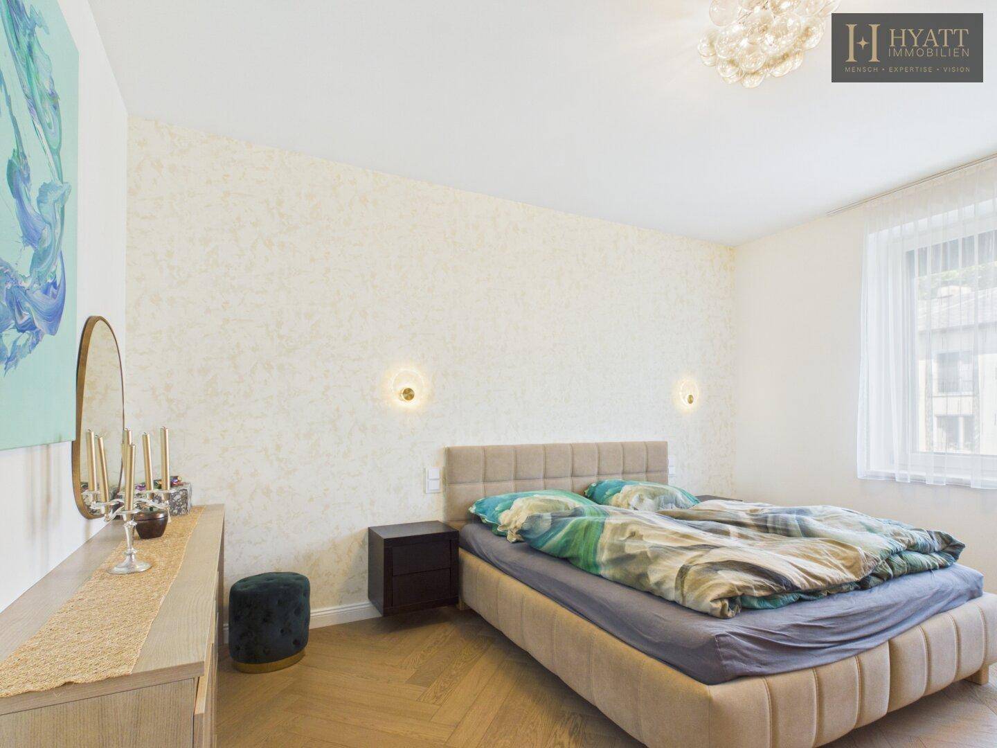 Helles Schlafzimmer mit gemütlichem Bett, Nachttisch und Fenster mit Blick auf die Umgebung.