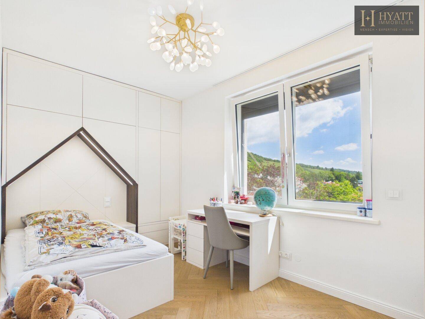 Kinderzimmer mit kreativem Bett, Schreibtisch, Einbauschrank und großem Fenster mit schöner Aussicht.