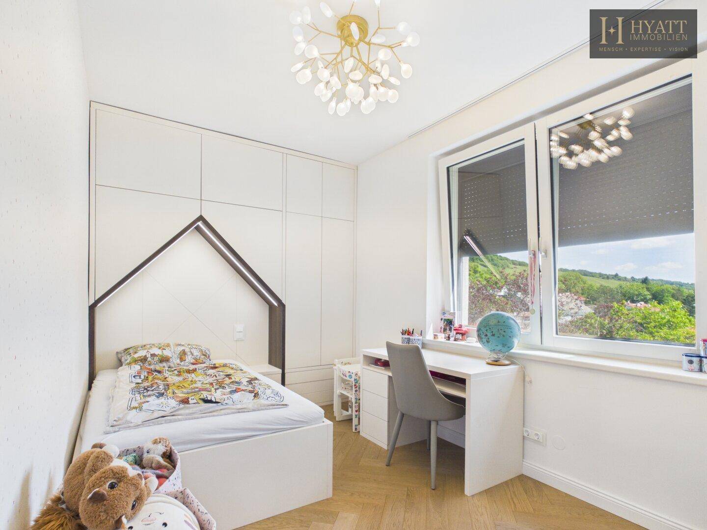 Freundliches Kinderzimmer mit Hausbett, Schreibtisch und Einbauschrank, hell und mit Ausblick.