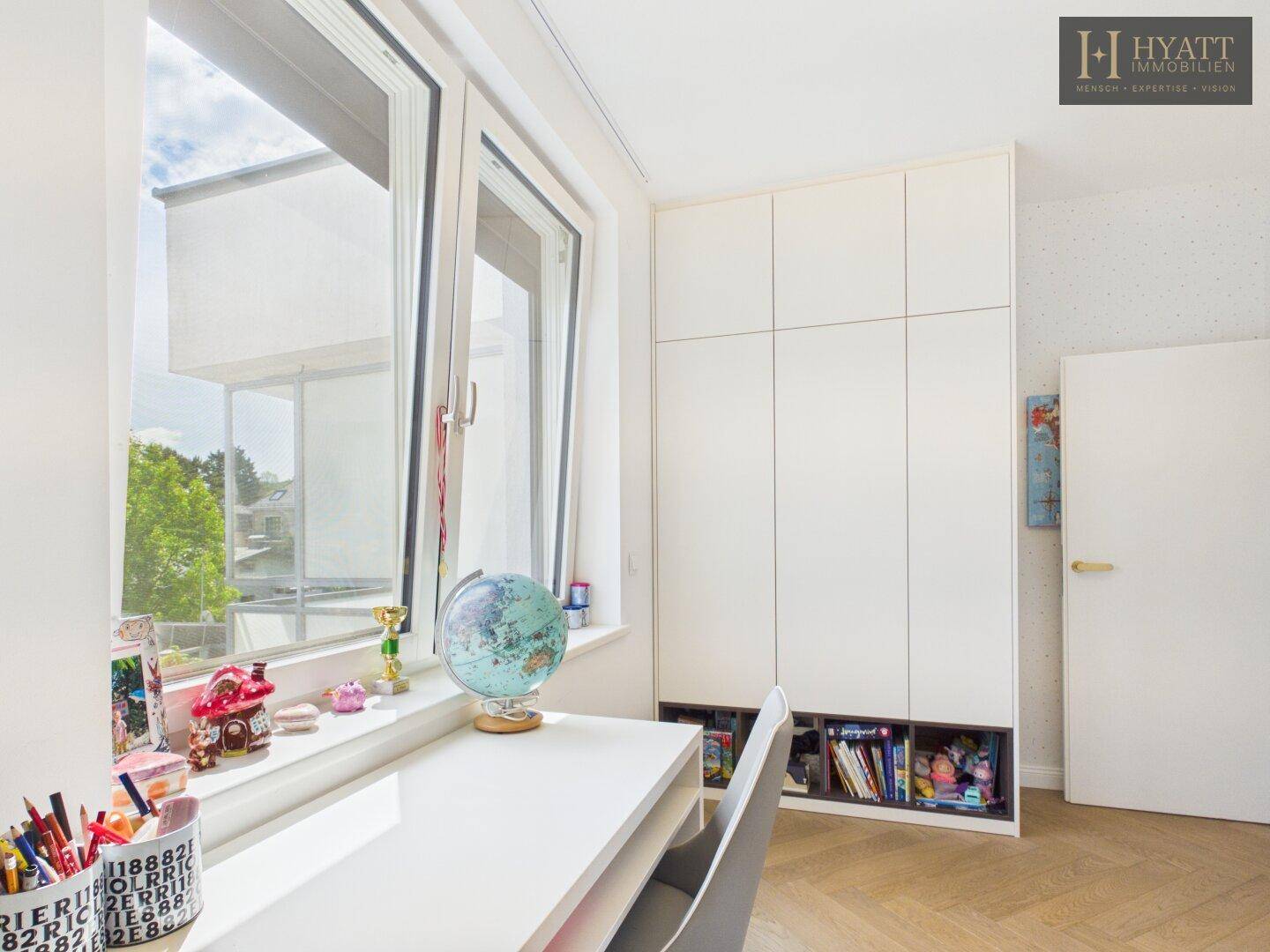 Detailansicht des Schreibtischbereichs im Kinderzimmer mit Einbauschrank und Blick nach draußen.