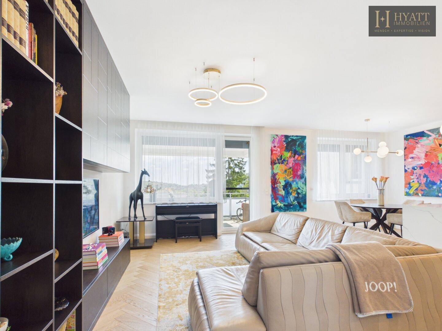 Heller offener Wohn-Essbereich mit Sofa, Esstisch und integrierter Küche, ideal für geselliges Beisammensein.